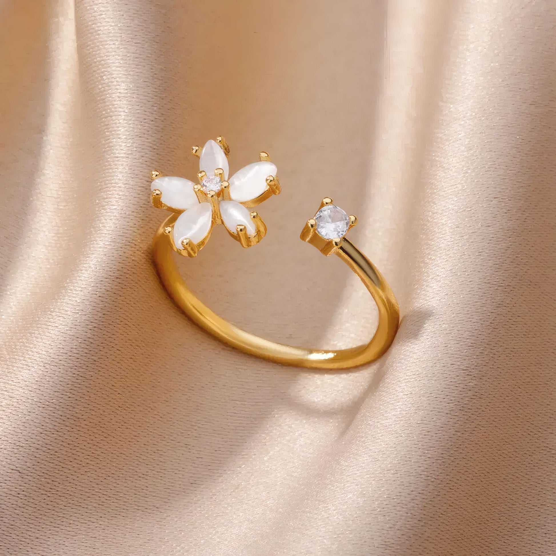 Gold Delphine Ring with floral opal centrepiece and open band, styled on soft champagne satin.