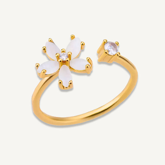 Delphine Ring in 18k gold-plated stainless steel with white flower detail and CZ stone, shown on white background.